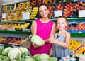 Cheerful woman with girl buying cabbage in grocery shop Royalty Free Stock Photo