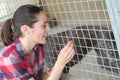 Cheerful woman gives dog sweets through fence