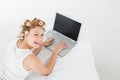 Cheerful woman in hair curlers using laptop in bed Royalty Free Stock Photo