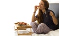 Cheerful Woman having breakfast in bed. Tea and pancakes with strawberry. Asian caucasian woman smiling looking at camera and Royalty Free Stock Photo