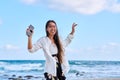 Cheerful woman in headphones with smartphone listening to music dancing on beach Royalty Free Stock Photo