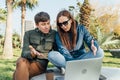 Cheerful woman and her male friend using laptop in public city park. Young couple people smiling while working together Royalty Free Stock Photo