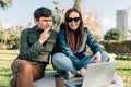 Cheerful woman and her male friend using laptop in public city park. Young couple people smiling while working together Royalty Free Stock Photo