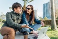 Cheerful woman and her male friend using laptop in public city park. Young couple people smiling while working together Royalty Free Stock Photo