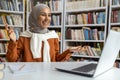 Cheerful woman in hijab interacting during video call at library