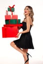 Cheerful woman hold stack of christmas gifts. Happy young female in black dress with heap of present Royalty Free Stock Photo