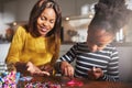 Cheerful woman holding beads for child at table