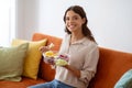 Cheerful woman holding bowl of fruit salad, enjoying healthy snack at home Royalty Free Stock Photo