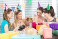 Cheerful woman holding a gift box during a surprise birthday party