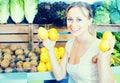 Cheerful woman holding lemons in hands in fruit store Royalty Free Stock Photo