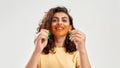 Cheerful woman holding orange film in front of her mouth, posing isolated over light background