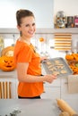 Cheerful woman holding tray of uncooked Halloween biscuits