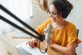 Female podcaster making audio stream in her small studio