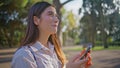 Cheerful woman messaging cellphone in park portraying happiness in digital age.