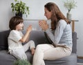 Cheerful woman nanny playing with funny boy clapping hands hitting palms relaxing at cozy home