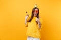 Cheerful woman in orange funny glasses, birthday hat with playing pipe showing thumb up, celebrating isolated on bright