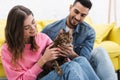 Cheerful woman petting bengal cat near