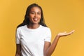 Cheerful woman pointing at copy space on her palm, empty place for idea presentation, product advertising. Indoor studio Royalty Free Stock Photo