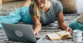 Cheerful woman portrait using laptop computer at home and reading a paper book - people enjoy relax and technology indoors - Royalty Free Stock Photo