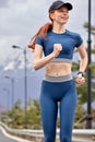 Cheerful woman runs in urban town, on the morning run. Mountains in the background Royalty Free Stock Photo