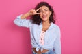Cheerful woman showing peace sign with her fingers, beautiful young female with curly hair showing victory sign and looks smiling Royalty Free Stock Photo