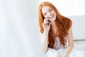 Cheerful woman sitting in bed and talking on mobile phone Royalty Free Stock Photo