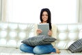 Cheerful woman sitting on the sofa and using tablet computer Royalty Free Stock Photo