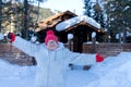 Cheerful woman stands and smiles happily in front of a rustic wooden house among the snowdrifts in the forest Royalty Free Stock Photo