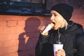 Cheerful woman in the street drinking morning coffee an d eat hot dog at winter time Royalty Free Stock Photo