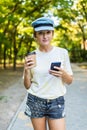 Cheerful woman in the street drinking morning coffee and use her smartphone. Young businesswoman using phone on the street. Woman Royalty Free Stock Photo