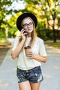 Cheerful woman in the street drinking morning coffee and use her smartphone. Young businesswoman using phone on the street. Woman Royalty Free Stock Photo