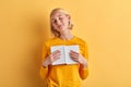 Cheerful woman in strylish yellow sweater with closed eyes hugging her diary