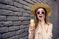 Cheerful woman in sunglasses with ice cream in hands outdoors black brick wall street style Royalty Free Stock Photo
