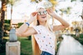 Cheerful young woman in sunglasses in summer palms backgrounds