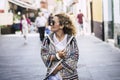 Cheerful woman in sunglasses walking on street on holidays. Young woman walking on street in jacket during winters. Young woman