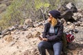 Cheerful woman in trekking rest activity with backpack and desert mountains background around - concept of travel alone and enjoy