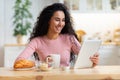 Cheerful Woman Using Digital Tablet While Having Breakfast In Kitchen At Home Royalty Free Stock Photo