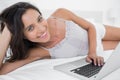 Cheerful woman using her laptop lying in bed Royalty Free Stock Photo