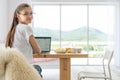 Cheerful woman using laptop at home. Young girl working on computer. Blogger, writer, journalist or student writing in Royalty Free Stock Photo