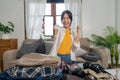 Cheerful woman using mobile phone blank white screen display frameless modern design while pack clothes a suitcase ready Royalty Free Stock Photo