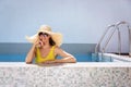 Cheerful woman wearing sunglasses and yellow swimsuit while relaxing in the swimming pool Royalty Free Stock Photo