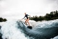 Cheerful woman in wetsuit rides down on surf style wakeboard on wave Royalty Free Stock Photo
