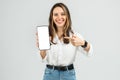 Cheerful woman in a white blouse and blue jeans showing a smartphone with a blank screen Royalty Free Stock Photo