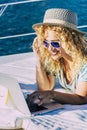 Cheerful woman work outdoor with laptop computer lay down on a boat enjoying freedom and internet connection - concept of people Royalty Free Stock Photo