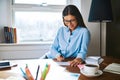 Cheerful woman writing checks at desk