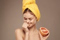 Cheerful woman with a yellow towel on her head bare shoulders grapefruit in hand natural cosmetics Royalty Free Stock Photo