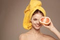 Cheerful woman with a yellow towel on her head bare shoulders grapefruit in hand natural cosmetics Royalty Free Stock Photo