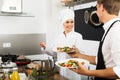 Cheerful woman cook giving salad to waitress Royalty Free Stock Photo