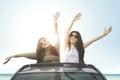 Cheerful women enjoying freedom on car sunroof