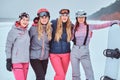 Cheerful women friends in sports winter clothes with snowboard, posing Royalty Free Stock Photo